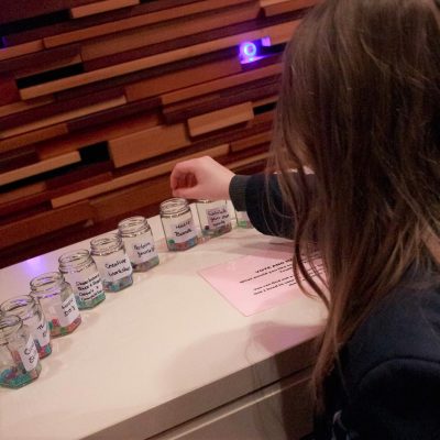 Girl putting a bead in one of 10 jars
