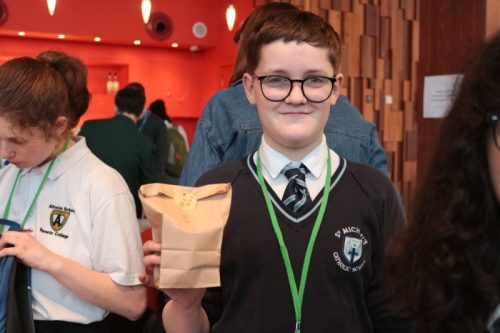 boy smiling and holding a paper bag